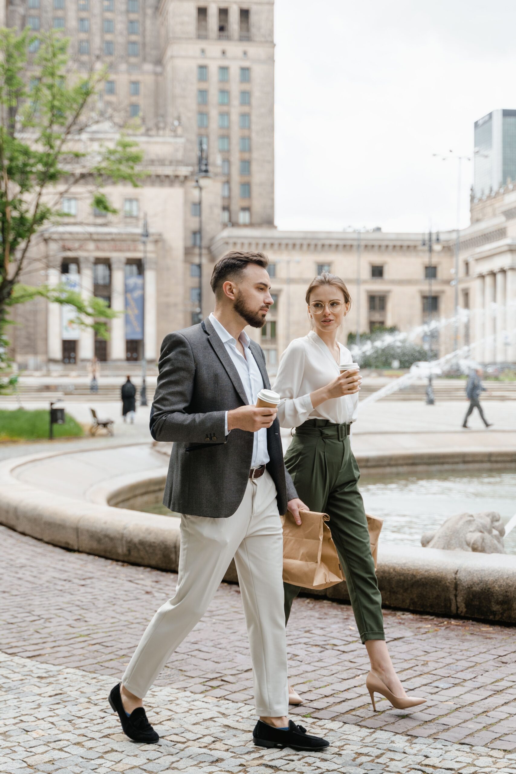 Two business professionals walking and conversing with coffee, showcasing modern urban lifestyle.